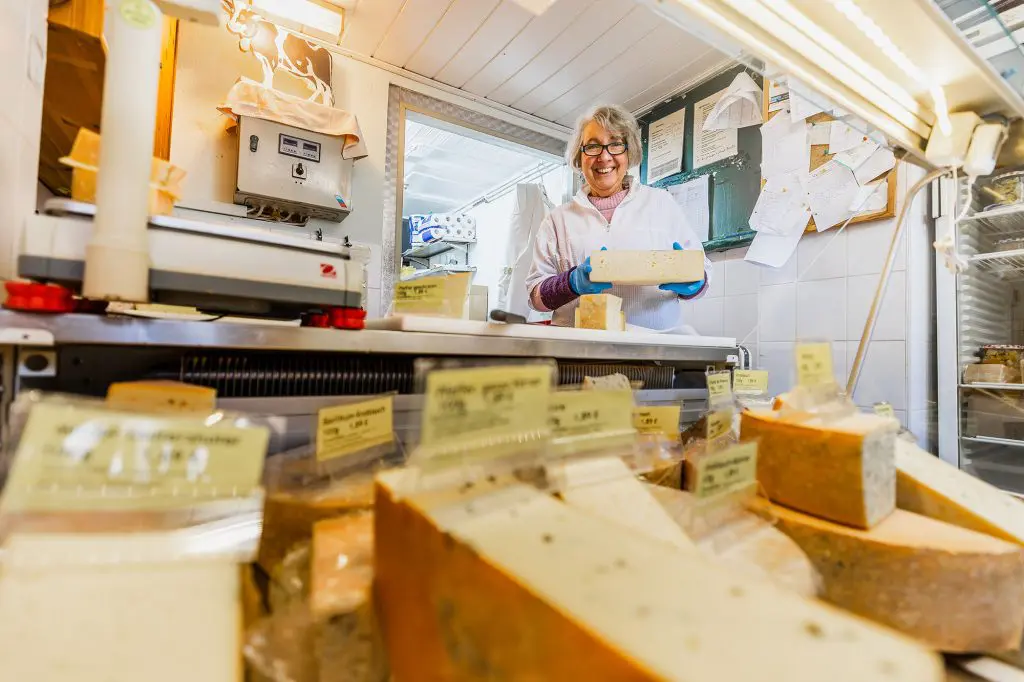Eine lächelnde Frau hinter der Käsetheke.