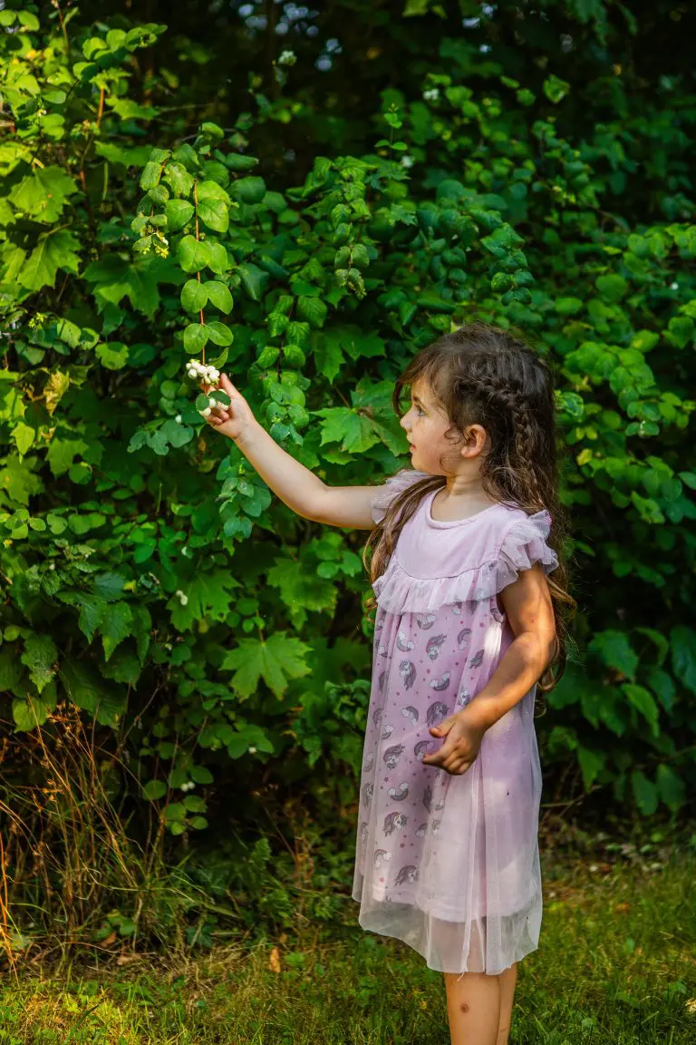 Ein junges Mädchen hält vorsichtig eine Handvoll Beeren, während sie neugierig die Natur inspiziert. Bild: Bernd Ulrich