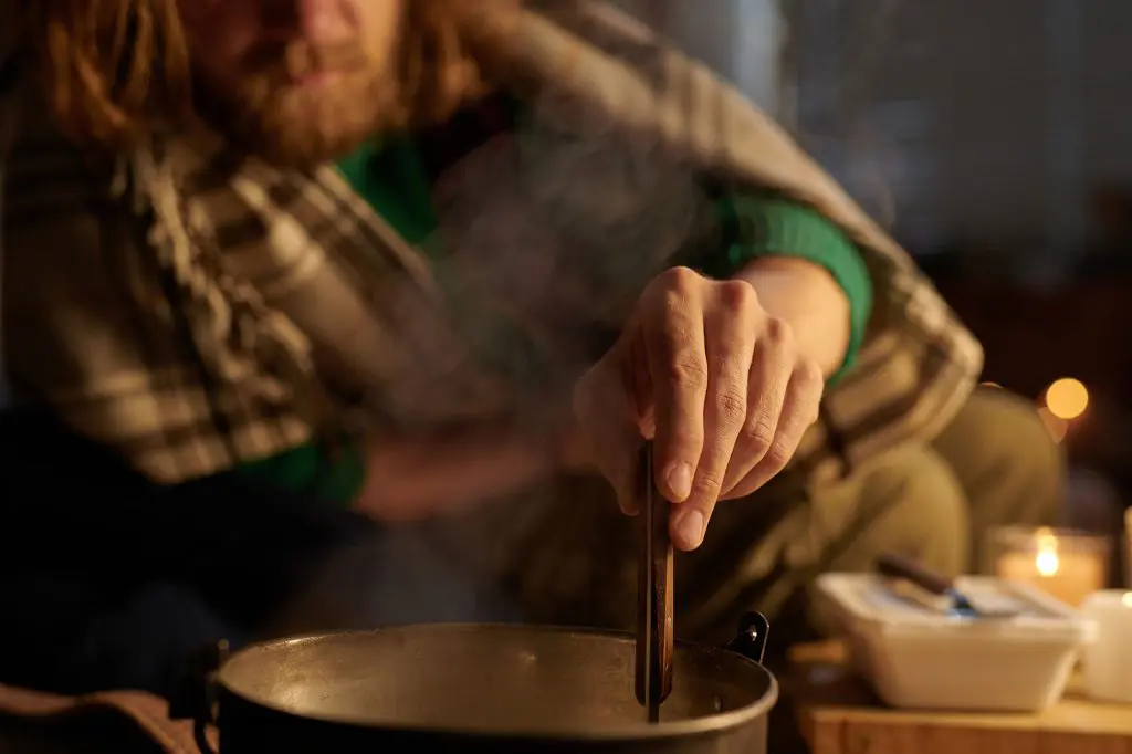 Suppe im Topf an einem kalten Winterabend bei Kerzenlicht rühren. Foto: Adobe Stock