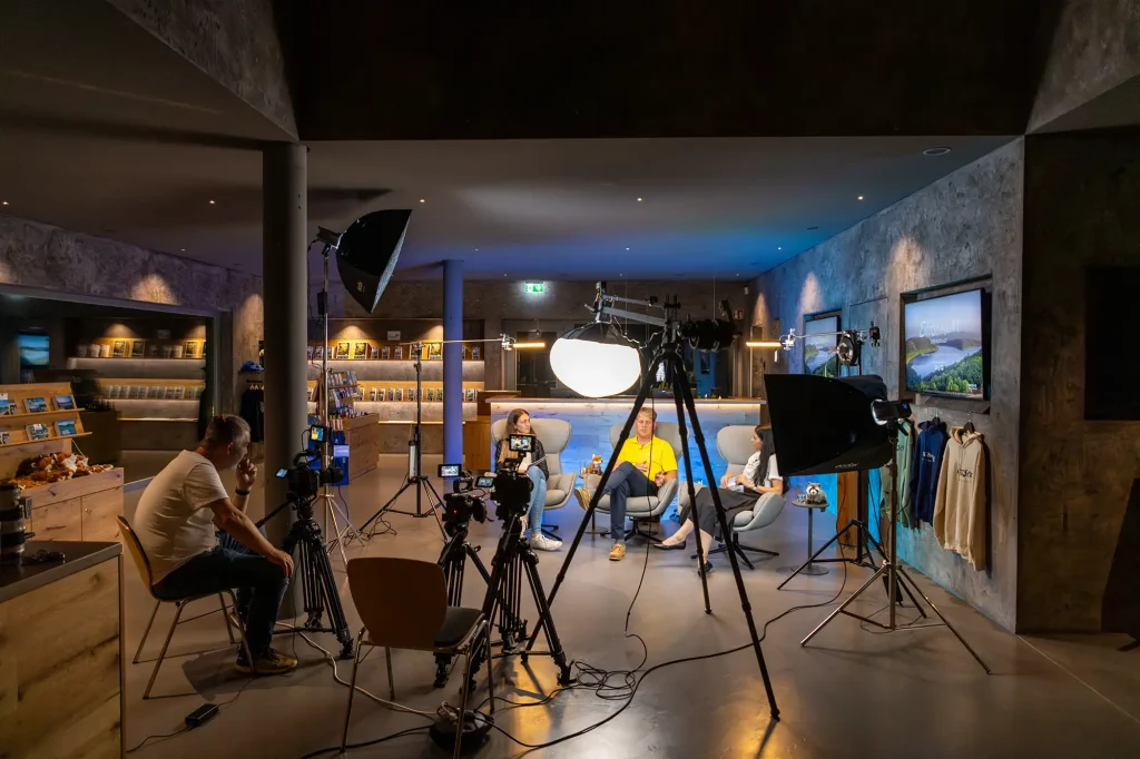 Drei Personen machen einen Podcast und man sieht Kameraequipment.