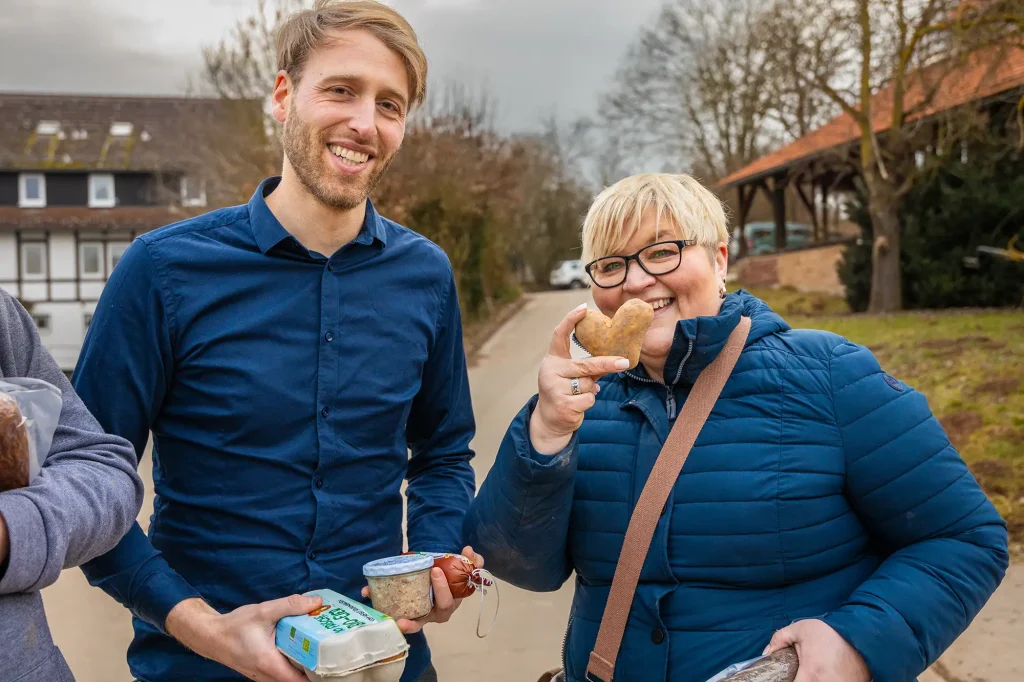 Zwei Personen grinsen in die Kamera mit Produkten aus dem örtlichen Hofgut Rocklinghausen
