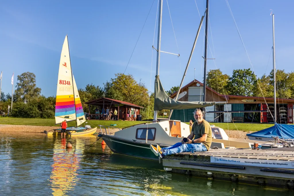 Marcus Brauer sitzt auf einem Segelboot mit seiner Kamera und bereitet sich auf eine Aufnahme vor.