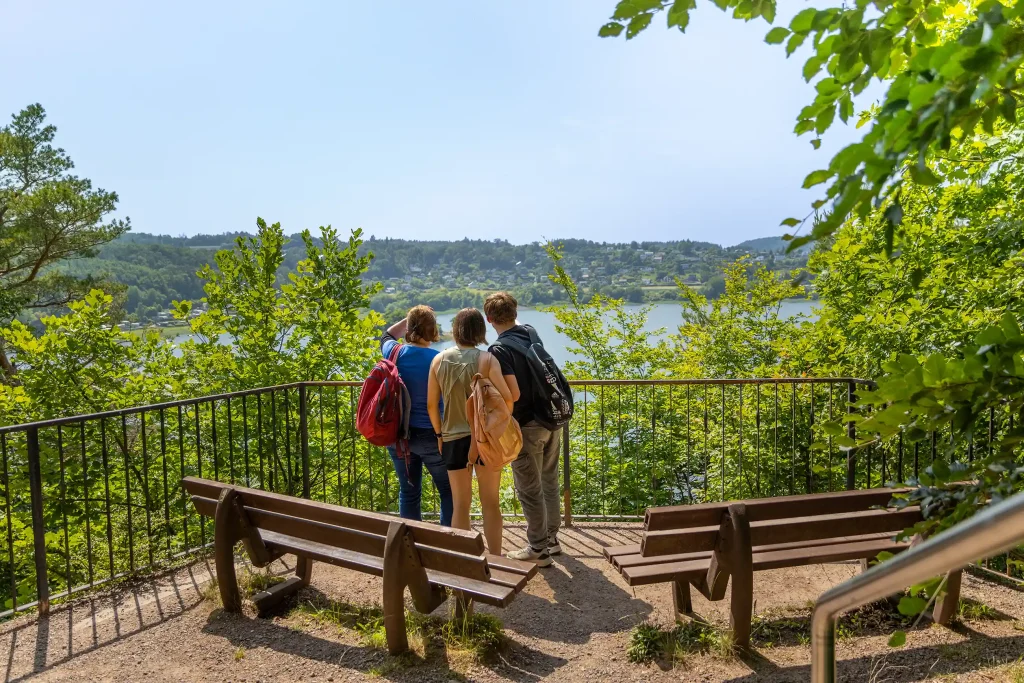 Drei Wanderer stehen an einer Sicherheitsabsperrung und blicken auf den Edersee.