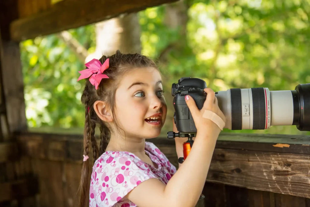 Kind schaut sich in einer versteckten Hütte, durch eine Kamera die Wasservögel an.
