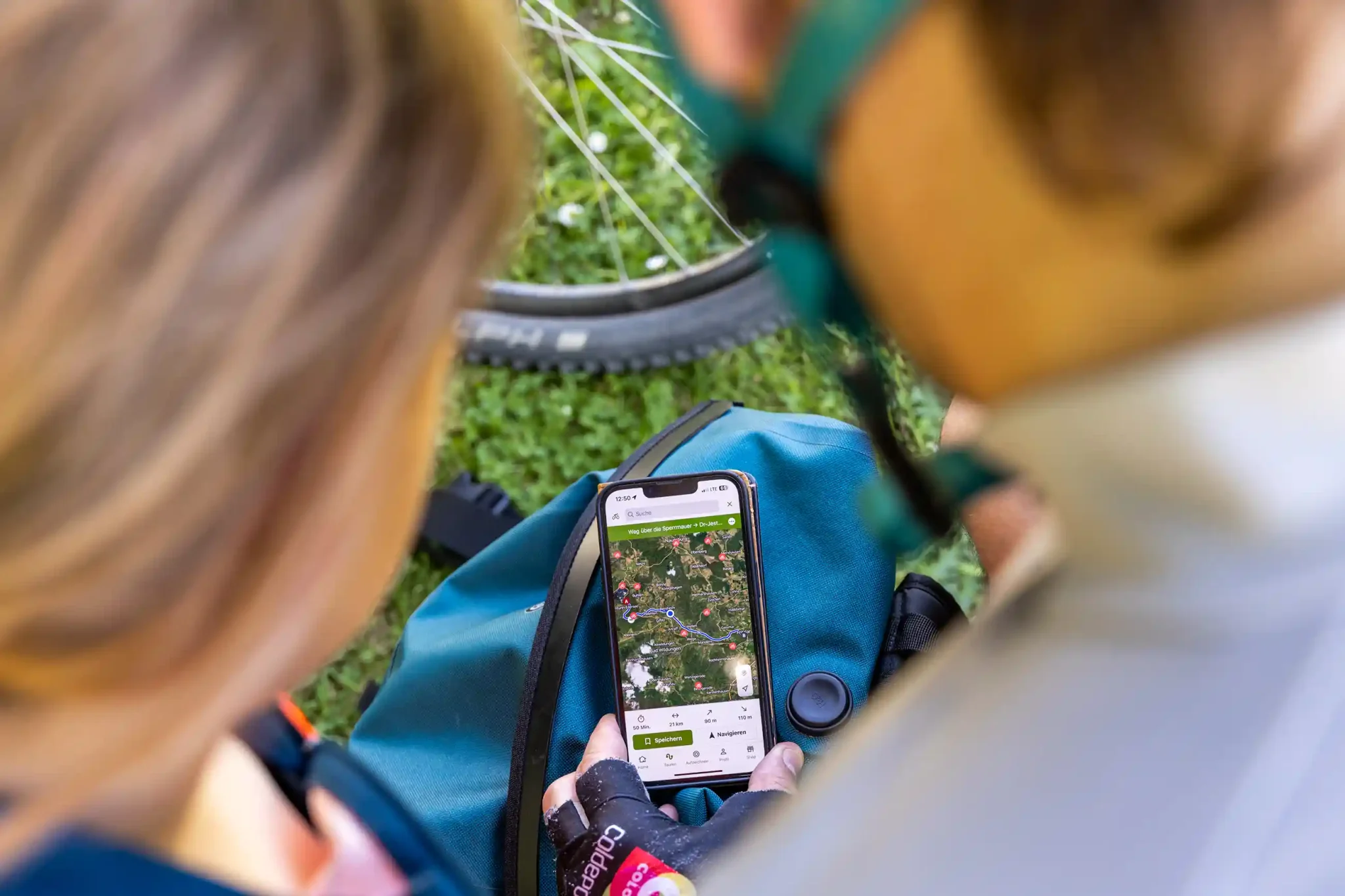Zwei Personen betrachten gemeinsam auf einem Smartphone eine Fahrradstrecke entlang des Eder-Radwegs.