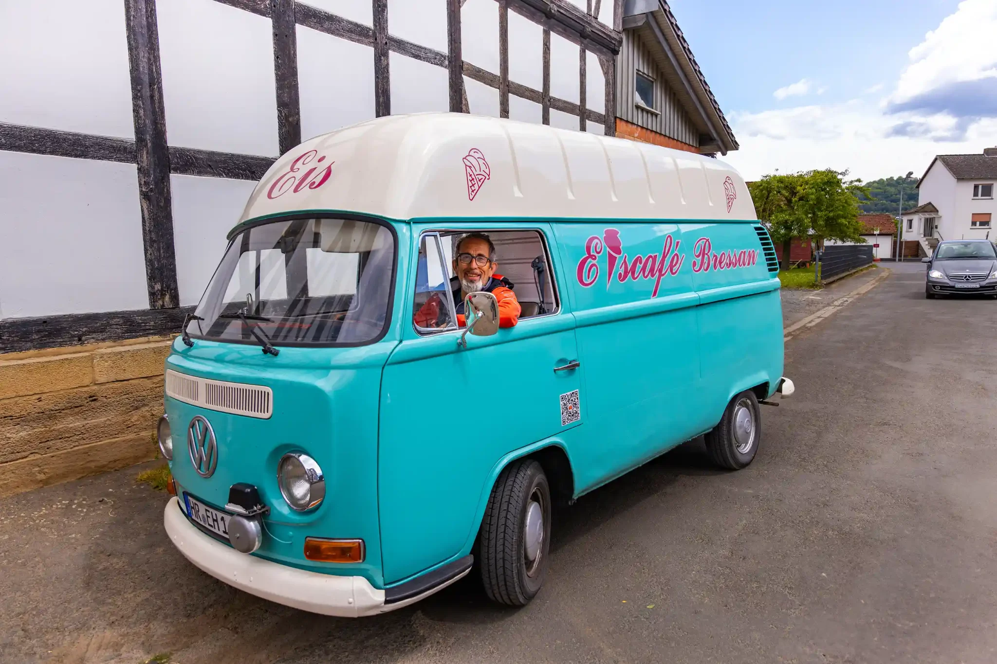 Ein lächelnder Mann sitzt im Innenraum seines Eiswagens.