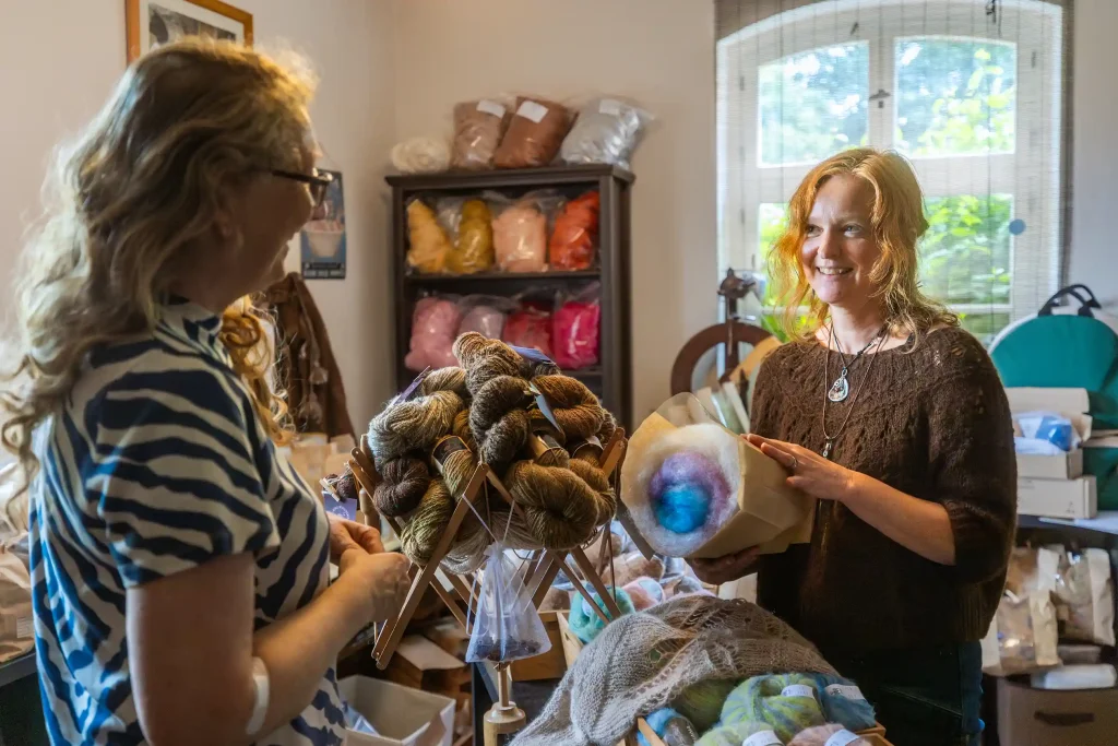 Daniela Munzert präsentiert Wolle in ihrem Hofladen in Neudorf, umgeben von handgefertigten Garnen und Wollprodukten. ©David Heise